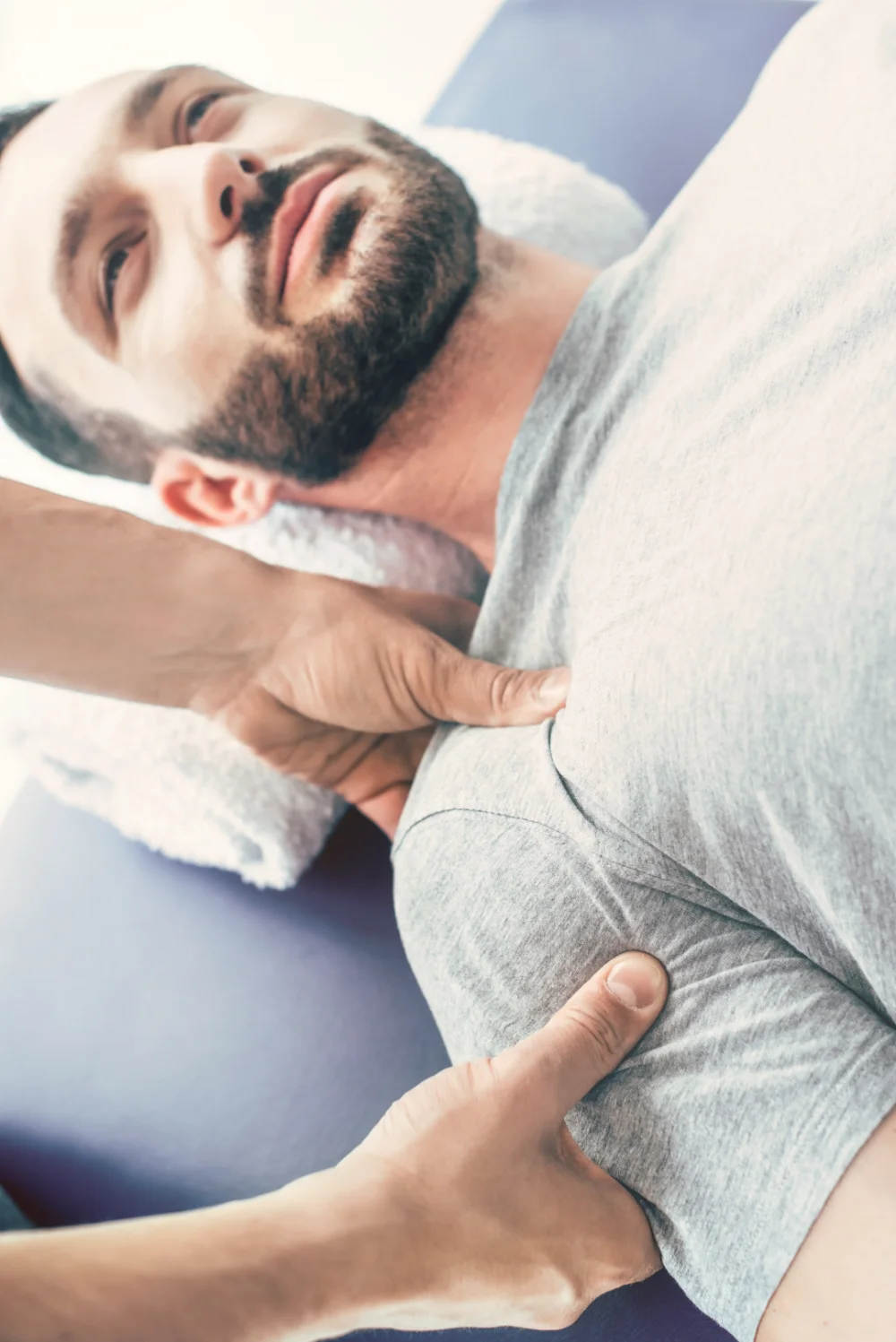 Physiotherapeut behandelt einen jungen Mann während einer Therapiesitzung