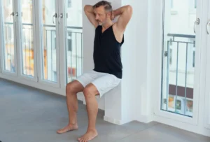 Mann mittleren Alters macht eine isomtrische Übung (Wall Sit), um seinen Blutdruck zu senken