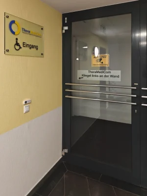 Eingangstür zur Praxis TheraMediCom. Hinweis auf Klingel für Rollstuhlfahrer zur persönlichen Türöffnung durch das Team.