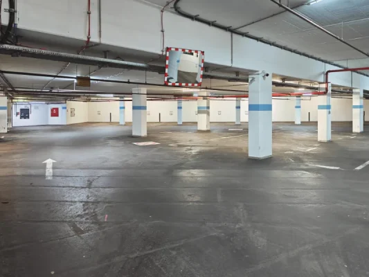 Innenansicht der Tiefgarage für Patienten der Physiotherapie TheraMediCom in Dortmund Innenstadt. Gut beleuchtete, breite Stellplätze im Untergeschoss mit Zugang zum Aufzug.