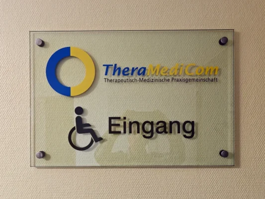 Praxisschild TheraMediCom mit Rollstuhl-Symbol kennzeichnet den barrierefreien Eingang.